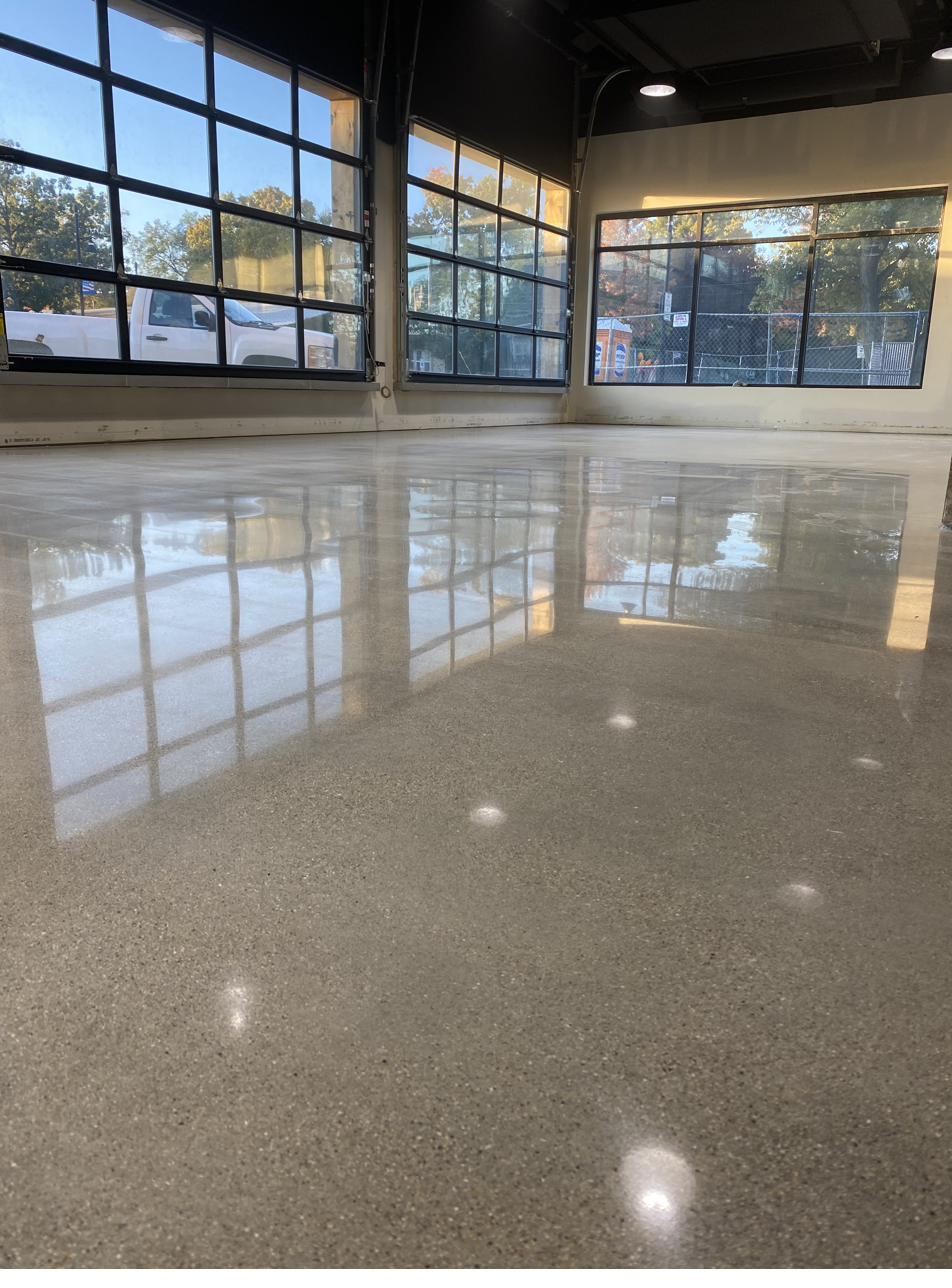 Glossy polished concrete floor in a commercial showroom with garage doors